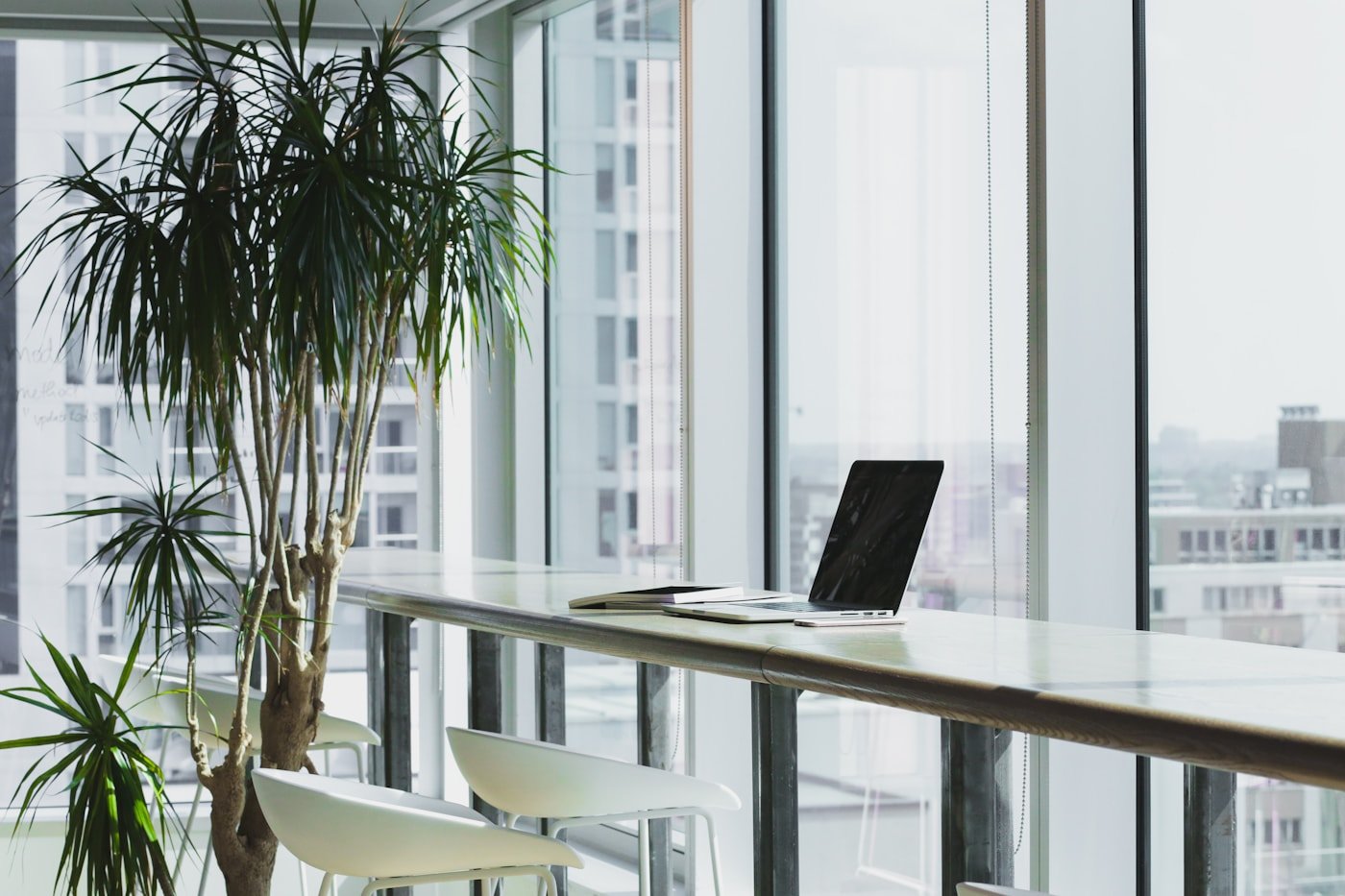 Bancada de trabalho junto à janela, com superfície contínua e notebook.